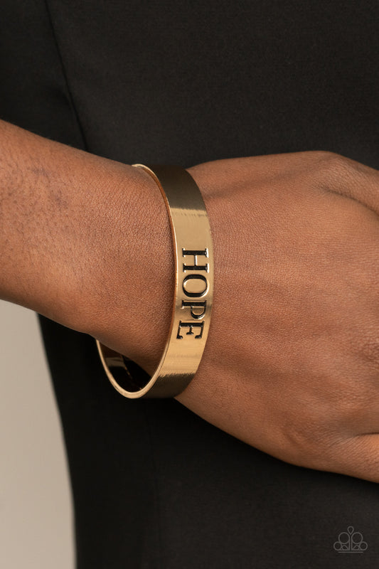 Hope Makes The World Go Round Gold Cuff Bracelet - Paparazzi Accessories  The center of a shiny gold cuff is stamped in the word, "Hope," for an inspirational look.  Sold as one individual bracelet.