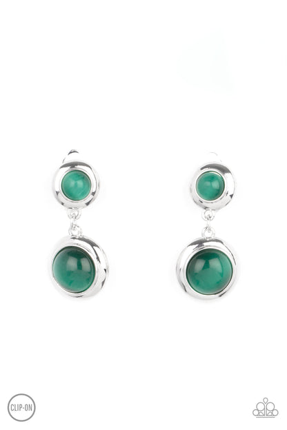Subtle Smolder Green Clip-On Earring - Paparazzi Accessories  Encased in sleek silver fittings, two green cat's eye stones link into a whimsical lure. Earring attaches to a standard clip-on fitting.  All Paparazzi Accessories are lead free and nickel free!  Sold as one pair of clip-on earrings.