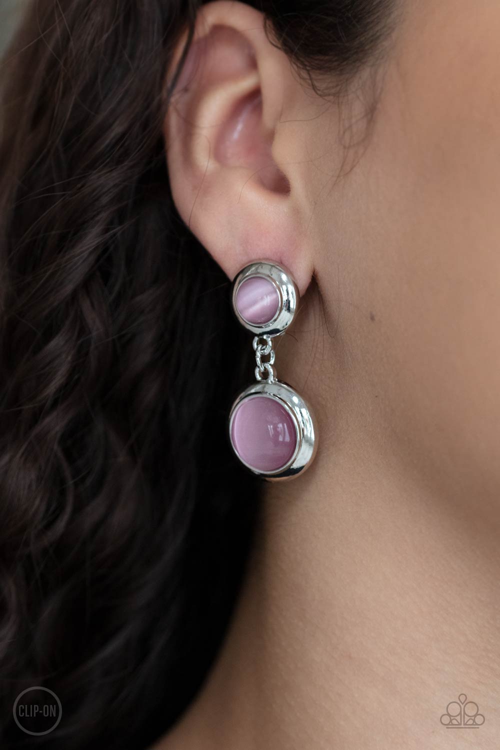 Subtle Smolder Pink Clip-On Earring - Paparazzi Accessories  Encased in sleek silver fittings, two pink cat's eye stones link into a whimsical lure. Earring attaches to a standard clip-on fitting.  All Paparazzi Accessories are lead free and nickel free!  Sold as one pair of clip-on earrings.