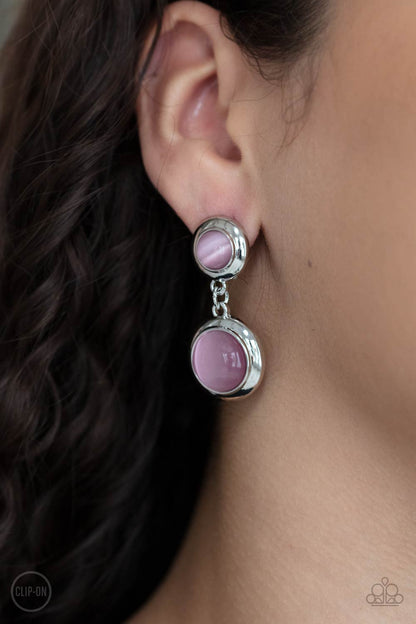 Subtle Smolder Pink Clip-On Earring - Paparazzi Accessories  Encased in sleek silver fittings, two pink cat's eye stones link into a whimsical lure. Earring attaches to a standard clip-on fitting.  All Paparazzi Accessories are lead free and nickel free!  Sold as one pair of clip-on earrings.