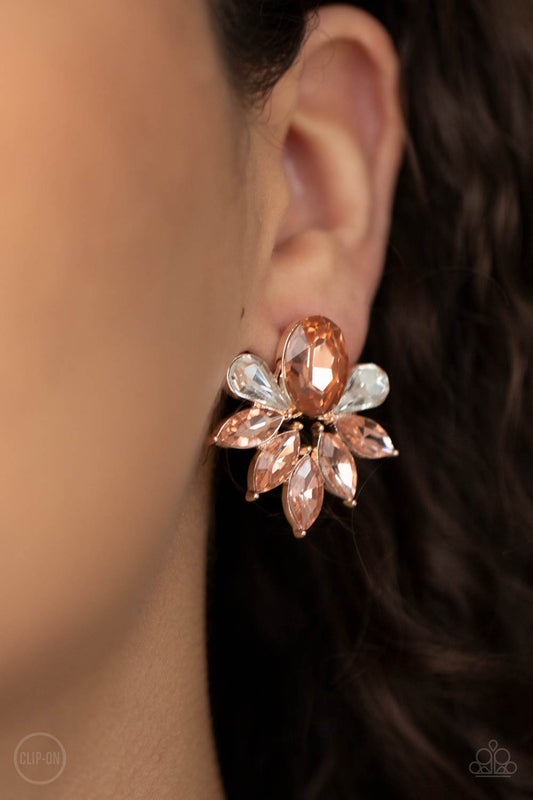 Fearless Finesse Rose Gold Clip-On Earring - Paparazzi Accessories  A glassy collection of white teardrop and rose gold marquise cut rhinestones fan out from the bottom of an oval rose gold gem, creating a majestic centerpiece. Earring attaches to a standard clip-on earring.  ﻿All Paparazzi Accessories are lead free and nickel free!  Sold as one pair of clip-on earrings.