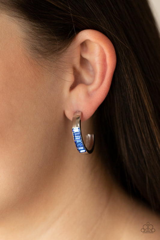 Bursting With Brilliance Blue Hoop Earring - Paparazzi Accessories  The front of a thick silver hoop is encrusted in glittery blue emerald cut rhinestones, creating a glamorous pop of color. Earring attaches to a standard post fitting. Hoop measures approximately 1" in diameter.  All Paparazzi Accessories are lead free and nickel free!  Sold as one pair of hoop earrings.