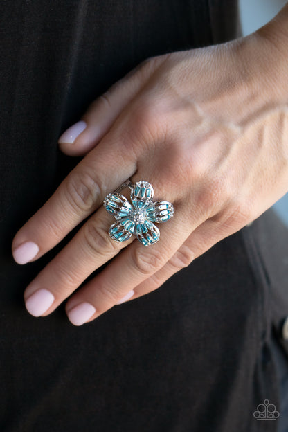 Botanical Ballroom Blue Ring - Paparazzi Accessories  Blue emerald-style rhinestones adorn the silver petals of a blooming flower featuring a white rhinestone encrusted beaded center. The tips of the colorful petals are dusted in dainty white rhinestones, adding extra shimmer to the sparkly centerpiece. Features a stretchy band for a flexible fit.  All Paparazzi Accessories are lead free and nickel free!  Sold as one individual ring.
