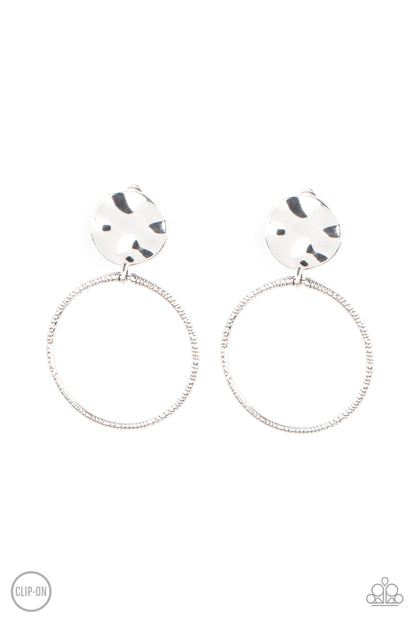 Undeniably Urban Silver Clip-On Earring - Paparazzi Accessories  A textured silver hoop attaches to a hammered silver disc, creating an edgy hoop. Earring attaches to a standard clip-on fitting.  All Paparazzi Accessories are lead free and nickel free!  Sold as one pair of clip-on earrings.