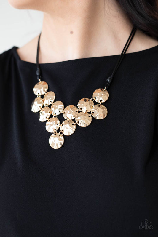 Token Treasure Gold Necklace - Paparazzi Accessories  Featuring a hammered finish, a collection of glistening gold discs delicately connect into a netted pendant at the bottom of knotted black cords for a statement-making look. Features an adjustable clasp closure.  All Paparazzi Accessories are lead free and nickel free!  Sold as one individual necklace. Includes one pair of matching earrings.