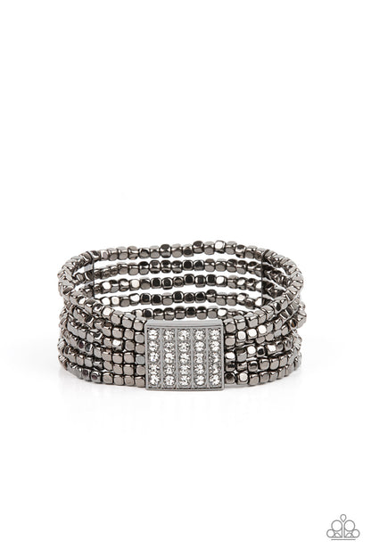 Star-Studded Showcase Black Bracelet - Paparazzi Accessories  Held in place by a square centerpiece encrusted in row after row of dazzling white rhinestones, a dainty collection of gunmetal cube beads are threaded along stretchy bands around the wrist, creating shimmery layers.  All Paparazzi Accessories are lead free and nickel free!  Sold as one individual bracelet.