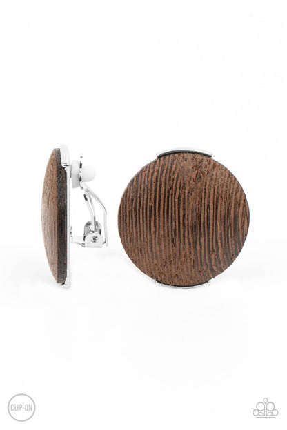 WOODWORK It Brown Clip-On Earring - Paparazzi Accessories  An oversized brown wooden disc is fitted in place between a silver frame, creating an earthy effect. Earring attaches to a standard clip-on fitting.  All Paparazzi Accessories are lead free and nickel free!  Sold as one pair of clip-on earrings.