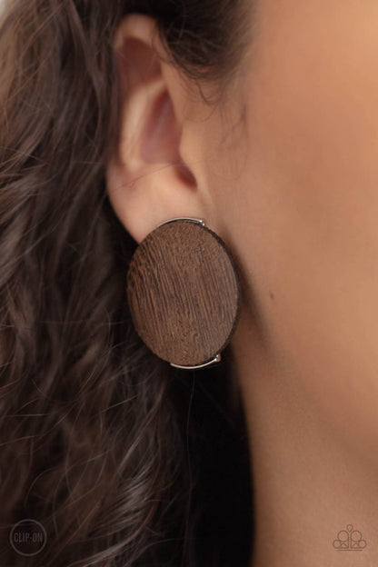 WOODWORK It Brown Clip-On Earring - Paparazzi Accessories  An oversized brown wooden disc is fitted in place between a silver frame, creating an earthy effect. Earring attaches to a standard clip-on fitting.  All Paparazzi Accessories are lead free and nickel free!  Sold as one pair of clip-on earrings.