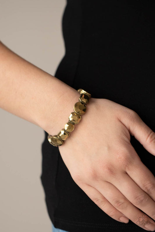 Extra Exposure Brass Bracelet - Paparazzi Accessories  Encased in sleek brass frames, a smoldering collection of round and emerald cut aurum rhinestones glide along stretchy bands around the wrist, creating a sparkly industrial statement piece.  All Paparazzi Accessories are lead free and nickel free!   Sold as one individual bracelet.