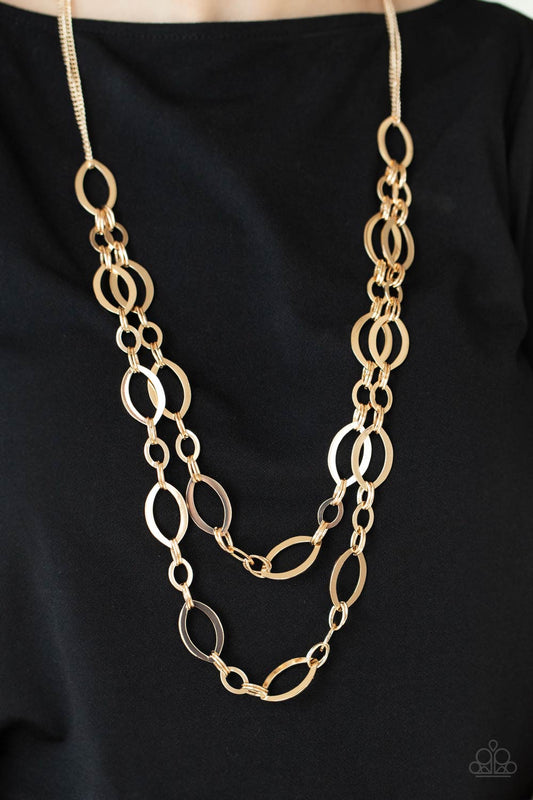 The OVAL-achiever Gold Necklace - Paparazzi Accessories  Stunning gold ellipses link together for two layers of bold, basic drama. The layers hang from a simple gold chain adding balance to the scene. Features an adjustable clasp closure.  Sold as one individual necklace. Includes one pair of matching earrings.