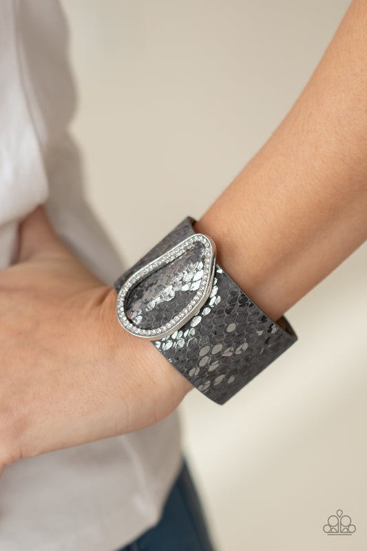 HISS-tory In The Making Silver Wrap Bracelet - Paparazzi Accessories  Encrusted with glassy white rhinestones, an asymmetrical silver fitting glides along a gray leather band adorned in a metallic python print for a wild look. Features an adjustable snap closure.  Sold as one individual bracelet.