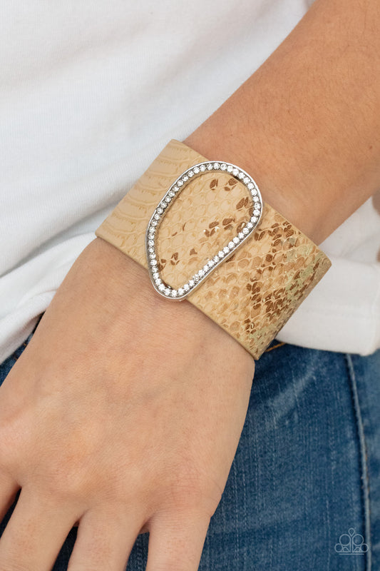 HISS-tory In The Making Brown Wrap Bracelet - Paparazzi Accessories  Encrusted with glassy white rhinestones, an asymmetrical silver fitting glides along a tan leather band adorned in a golden metallic python print for a wild look. Features an adjustable snap closure.  All Paparazzi Accessories are lead free and nickel free!  Sold as one individual bracelet.