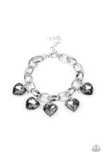 Candy Heart Charmer Silver Bracelet - Paparazzi Accessories  Smoky heart-shaped gems are encased in sleek silver frames that swing from an oversized silver chain, creating a sparkly fringe around the wrist. Features an adjustable clasp closure.  All Paparazzi Accessories are lead free and nickel free!  Sold as one individual bracelet.
