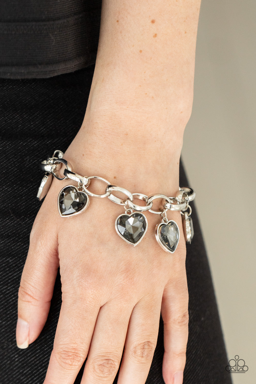 Candy Heart Charmer Silver Bracelet - Paparazzi Accessories  Smoky heart-shaped gems are encased in sleek silver frames that swing from an oversized silver chain, creating a sparkly fringe around the wrist. Features an adjustable clasp closure.  All Paparazzi Accessories are lead free and nickel free!  Sold as one individual bracelet.