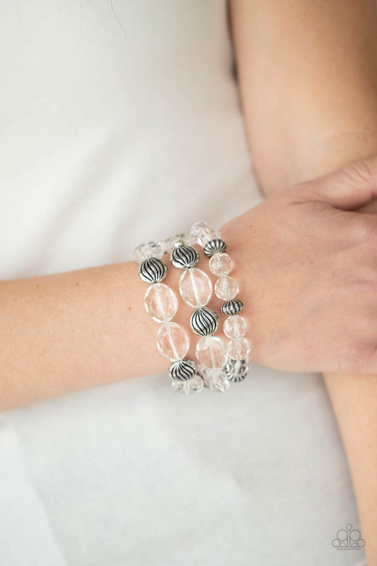 Crystal Charisma White Bracelet - Paparazzi Accessories A mismatched collection of sparkly white crystal-like beads and textured silver accents are threaded along stretchy bands around the wrist, creating glamorous layers.  ﻿All Paparazzi Accessories are lead free and nickel free!  Sold as one set of three bracelets.