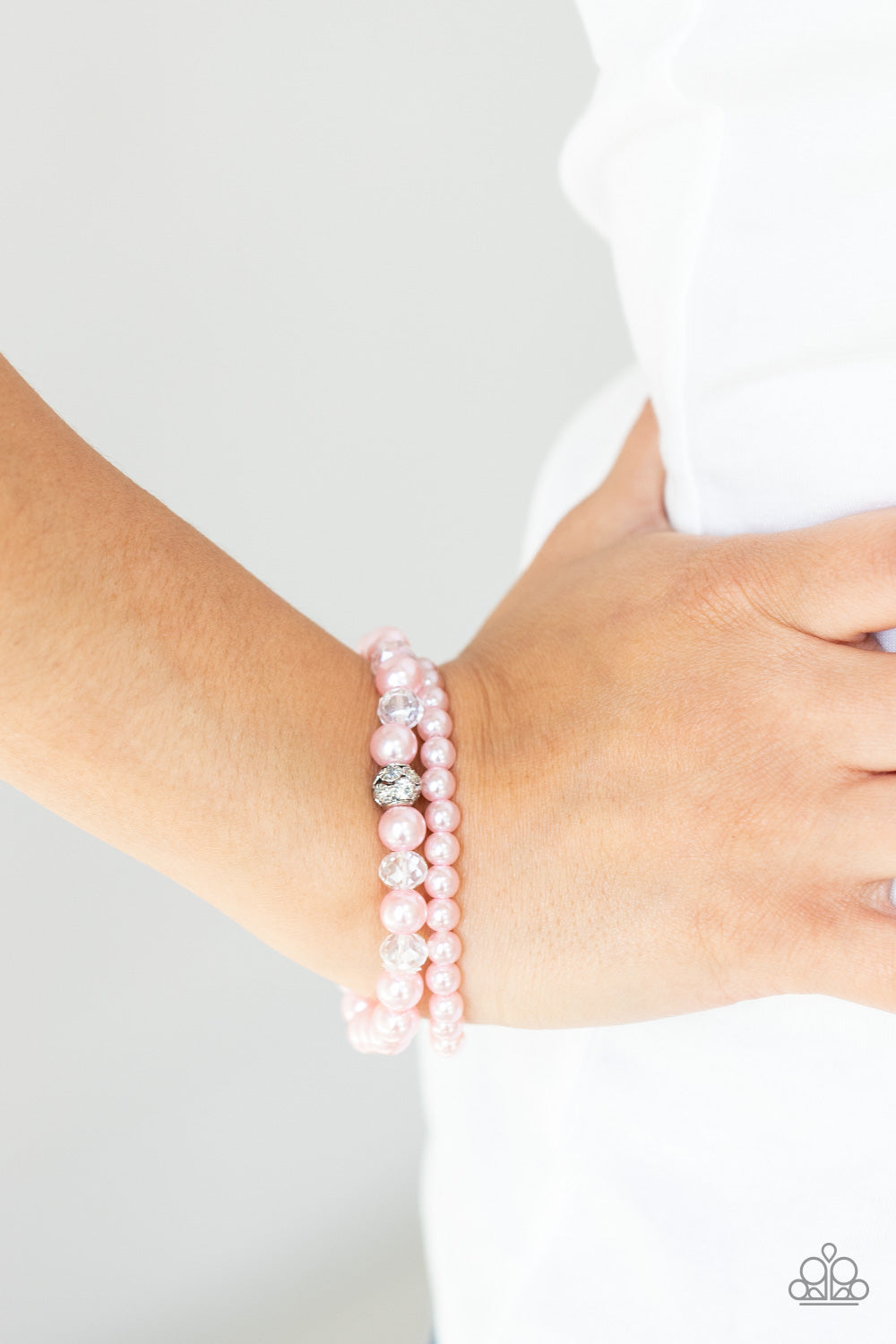 Cotton Candy Dreams Pink Bracelet - Paparazzi Accessories  A collection of dainty pink pearls and glassy crystal-like beads are threaded along two stretchy bands around the wrist, creating timeless layers. A white rhinestone encrusted silver bead adorns the center of one bracelet, creating a sparkly centerpiece.  Sold as one pair of bracelets.
