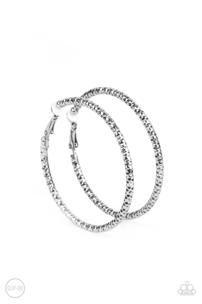 Subtly Sassy Silver Clip-On Earring - Paparazzi Accessories  An oversized silver hoop featuring a porous-like texture sends off a subtle shimmer as it wraps around the ear. Earring attaches to a standard clip-on fitting. Hoop measures approximately 2" in diameter.  Sold as one pair of clip-on earrings.