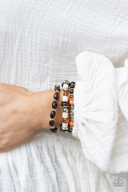 Belongs In The Wild Multi Bracelet - Paparazzi Accessories  A mismatched collection of brown wooden beads, silver accents, orange stones, Buttercream discs, and glassy Desert Mist beads are threaded along stretchy bands, creating colorful layers around the wrist.  Sold as one set of three bracelets.