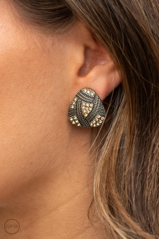 Gorgeously Galleria Brass Clip-On Earring - Paparazzi Accessories  Studded and textured ribbons of brass wrap around sections of golden topaz rhinestones, creating an edgy display. Earring attaches to a standard clip-on fitting.  ﻿All Paparazzi Accessories are lead free and nickel free!  Sold as one pair of clip-on earrings.