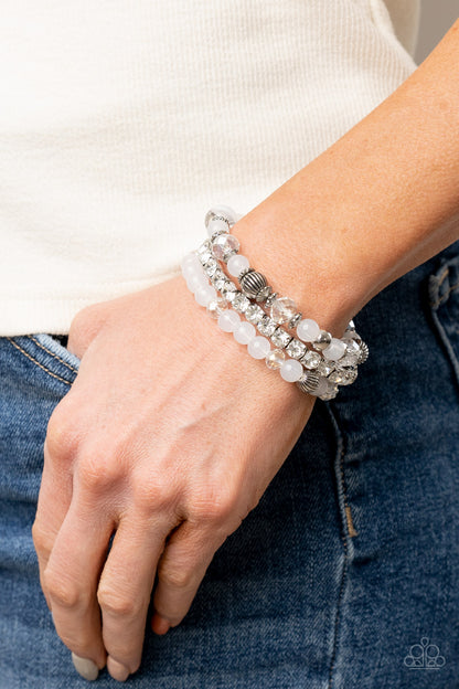 Ethereal Etiquette White Bracelet - Paparazzi Accessories.  Infused with a stretchy strand of glassy white rhinestones, a mismatched collection of cloudy white, white crystal-like, and ornate silver accents are threaded along stretchy bands around the wrist, creating ethereal layers.  ﻿﻿﻿All Paparazzi Accessories are lead free and nickel free!  Sold as one individual bracelet.