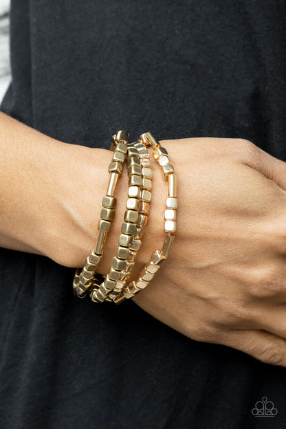 Metro Materials Multi Bracelet - Paparazzi Accessories  Lightweight and flirty, two strands of gold and brass square beads interspersed with gold cylinders, are paired with two strands of gold and brass cubes. The four stretchy bracelets come together to create an irresistible stack of metallic mayhem.  All Paparazzi Accessories are lead free and nickel free!  Sold as one set of four bracelets.