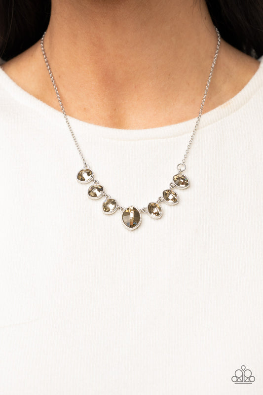 Material Girl Glamour Brown Necklace - Paparazzi Accessories  Encased in sleek silver fittings, elegant cut golden topaz rhinestones delicately connect below the collar. An oversized golden topaz rhinestone adorns to the middle of the glittery strand, creating a sparkly centerpiece. Features an adjustable clasp closure.  All Paparazzi Accessories are lead free and nickel free!  Sold as one individual necklace. Includes one pair of matching earrings.