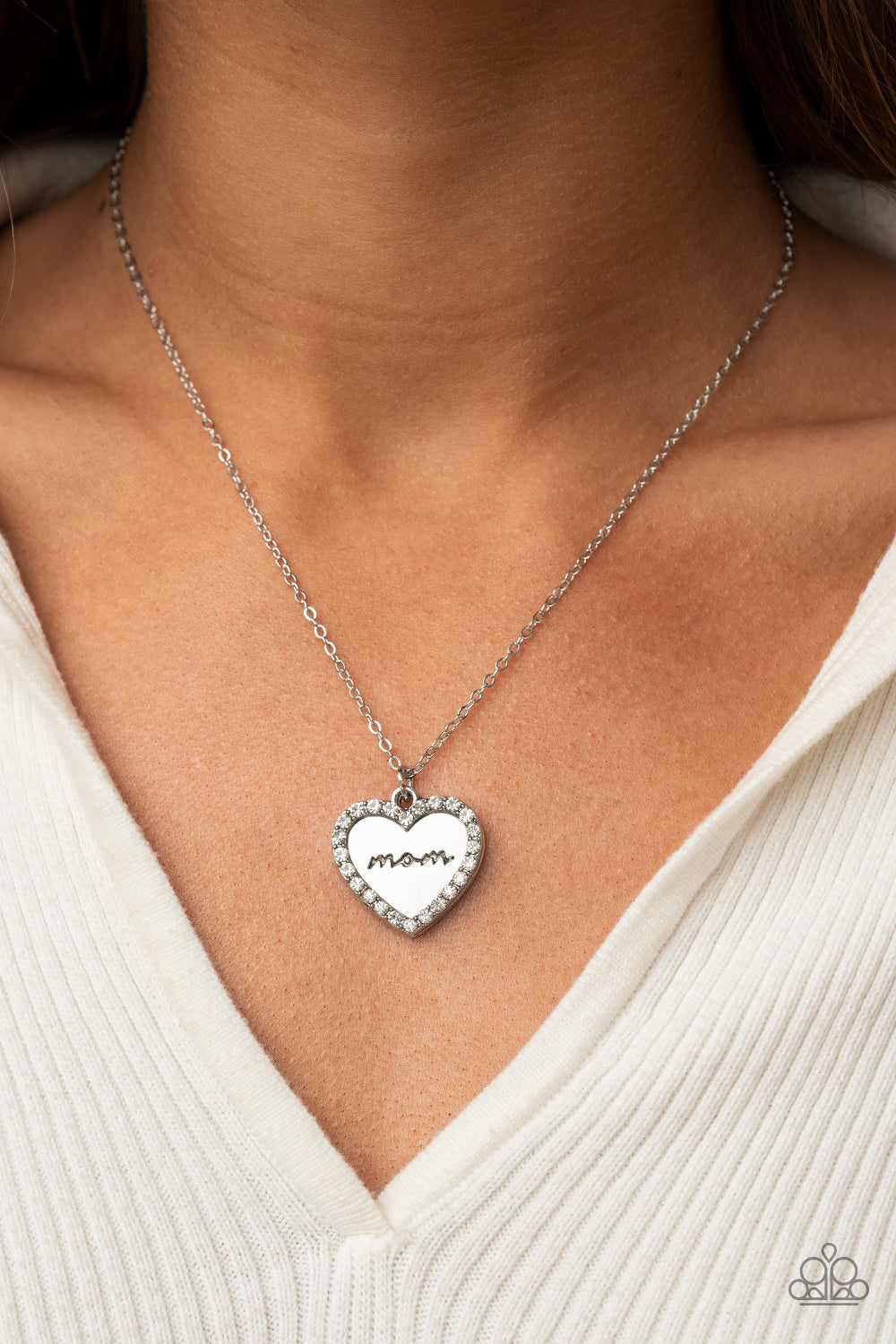 The Real Boss White Necklace - Paparazzi Accessories  Infused with a glassy white rhinestone encrusted silver heart, a silver heart shaped pendant is stamped in the word, "Mom," as it swings below the collar, creating a sparkly sentimental statement piece. Features an adjustable clasp closure.  Sold as one individual necklace. Includes one pair of matching earrings.