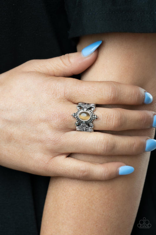 Reformed Refinement Brown Ring - Paparazzi Accessories  A glassy brown cat's eye stone is pressed into the center of a studded and metallic rope-like frame. Leafy floral bands delicately overlap the whimsical frame, coalescing into a tropical inspired centerpiece. Features a stretchy band for a flexible fit.  All Paparazzi Accessories are lead free and nickel free!   Sold as one individual ring.