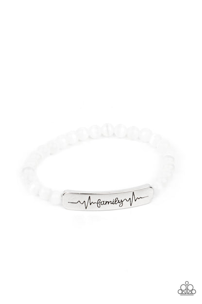 Family is Forever White Bracelet - Paparazzi Accessories  Stamped in heartbeats and the word, "Family," a shiny silver plate attaches to a strand of white cat's eye stone beads that are threaded along a stretchy band, creating a whimsically sentimental centerpiece around the wrist.  Sold as one individual bracelet.