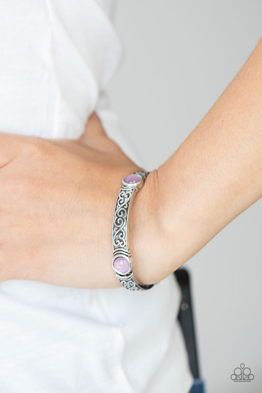 Ethereally Enchanting Purple Bracelet - Paparazzi Accessories  A purple cat's eye stone is pressed into a round frame at the end of a silver bar. Embossed with a whimsical vine motif, the patterned bars are threaded on stretchy bands to repeat around the wrist for an enchanting finish.  All Paparazzi Accessories are lead free and nickel free!  Sold as one individual bracelet.