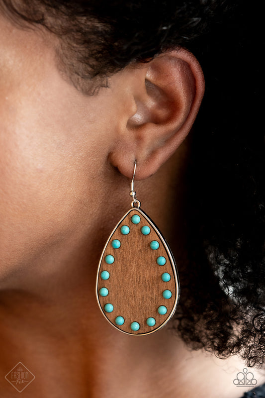 Rustic Refuge Blue Earring - Paparazzi Accessories.  Dainty turquoise stone beads border an earthy wooden teardrop frame that is encased in a sleek silver fitting, creating a whimsical woodsy lure. Earring attaches to a standard fishhook fitting.  ﻿All Paparazzi Accessories are lead free and nickel free!  Sold as one pair of earrings.