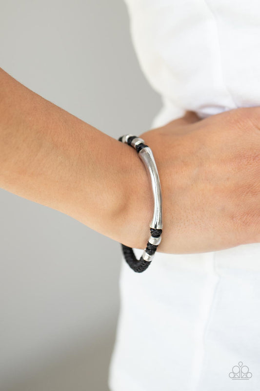 Grounded in Grit Black Urban Bracelet - Paparazzi Accessories Infused with asymmetrical brass beads, a rust brass bar is knotted in place across the center of a braided brown cord for an urban flair around the wrist. Features a button loop closure.  ﻿All Paparazzi Accessories are lead free and nickel free!   Sold as one individual bracelet.