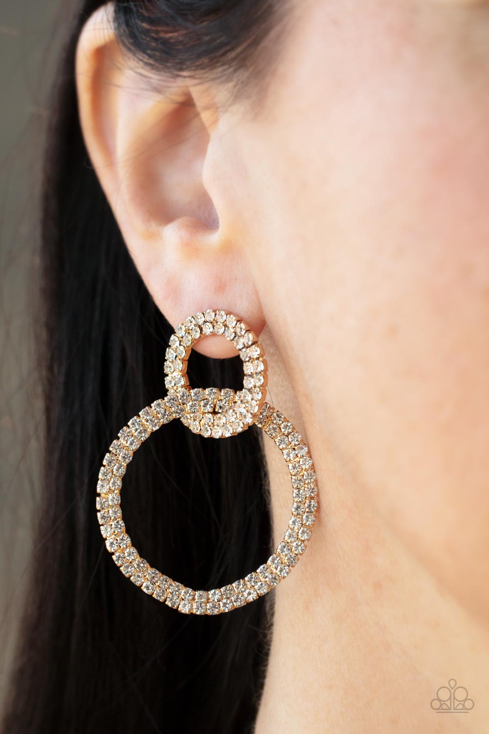 Intensely Icy Gold Post Earring - Paparazzi Accessories  Rows of sparkly white rhinestones encircle into two interconnected hoops, creating a jaw-dropping lure. Earring attaches to a standard post fitting.  Sold as one pair of post earrings.