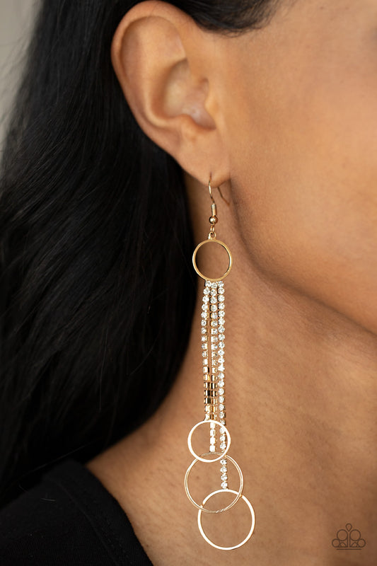 Demurely Dazzling Gold Earring - Paparazzi Accessories  Dainty gold hoops swing from the bottom of glittery strands of glassy white rhinestones that attach to the bottom of a dainty gold ring, creating a tantalizing tassel. Earring attaches to a standard fishhook fitting.  Sold as one pair of earrings.