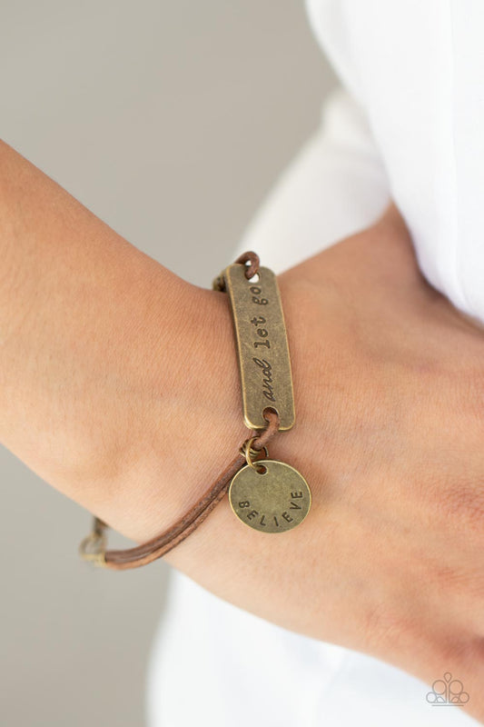 Believe and Let Go Brass Bracelet - Paparazzi Accessories  An antiqued disc stamped in the word, "believe" and a brass plate stamped in the phrase, "and let go," are knotted in place around the wrist with layers of brown suede cording, creating a motivational centerpiece. Features an adjustable clasp closure.  Sold as one individual bracelet.