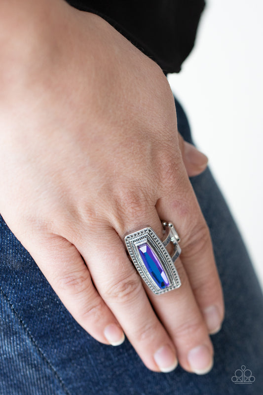 Luminary Luster Blue Ring - Paparazzi Accessories  An elongated UV gem is pressed into the center of a studded silver frame atop layered silver bands, creating a stellar centerpiece atop the finger. Features a stretchy band for a flexible fit.  Sold as one individual ring.