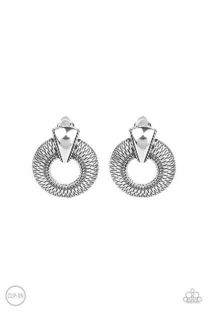 Industrial Innovator Silver Clip-On Earring - Paparazzi Accessories  Dainty sections of linear texture flare out from the center of an airy silver hoop that is adorned in an antiqued triangular accent, creating an edgy frame. Earring attaches to a standard clip-on fitting.  Sold as one pair of clip-on earrings.