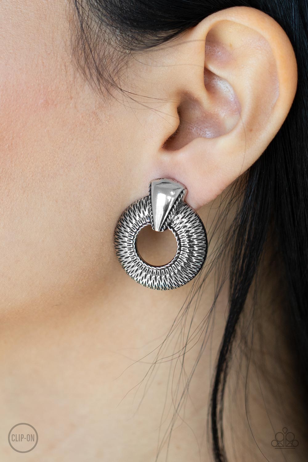 Industrial Innovator Silver Clip-On Earring - Paparazzi Accessories  Dainty sections of linear texture flare out from the center of an airy silver hoop that is adorned in an antiqued triangular accent, creating an edgy frame. Earring attaches to a standard clip-on fitting.  Sold as one pair of clip-on earrings.