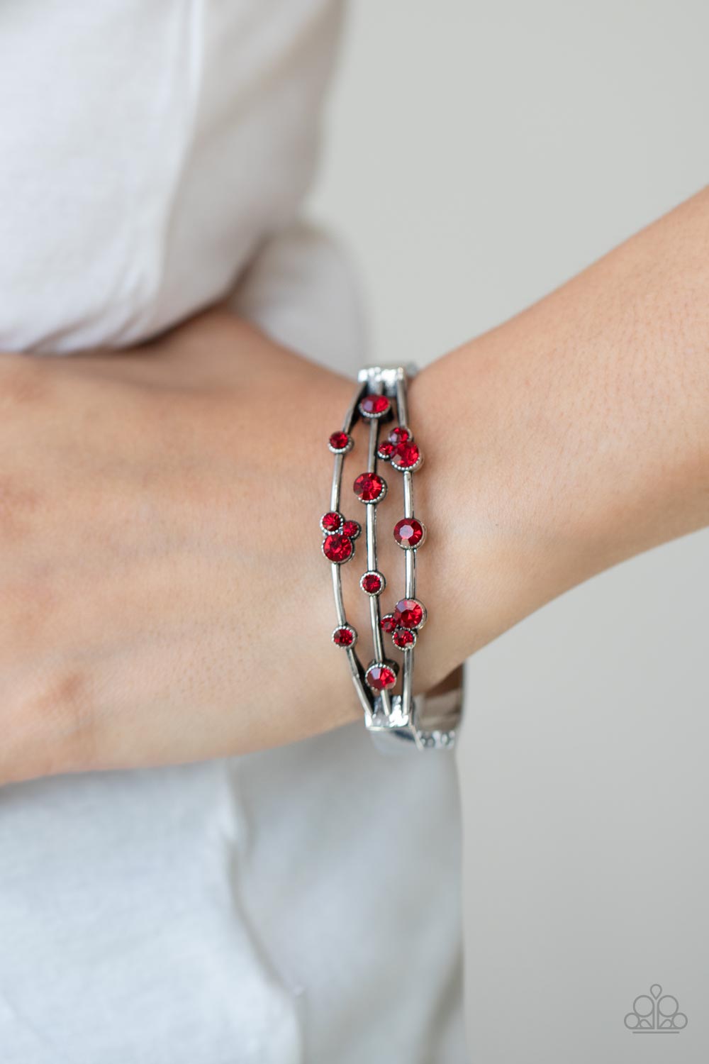 Cosmic Candescence Red Bracelet - Paparazzi Accessories  A smattering of fiery red rhinestones adorn three silver bars that coalesce into a versatile silver cuff-like bangle around the wrist. Features a hinged closure.  All Paparazzi Accessories are lead free and nickel free!  Sold as one individual bracelet.
