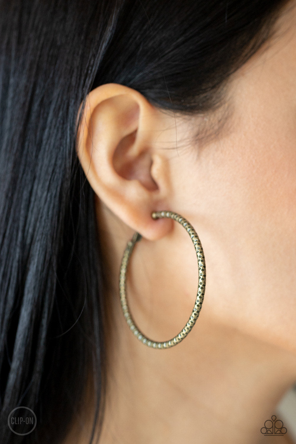 Subtly Sassy Brass Clip-On Hoop Earring - Paparazzi Accessories  An oversized brass hoop featuring a porous-like texture sends off a subtle shimmer as it wraps around the ear. Earring attaches to a standard clip-on fitting. Hoop measures approximately 2" in diameter.  All Paparazzi Accessories are lead free and nickel free!  Sold as one pair of earrings.