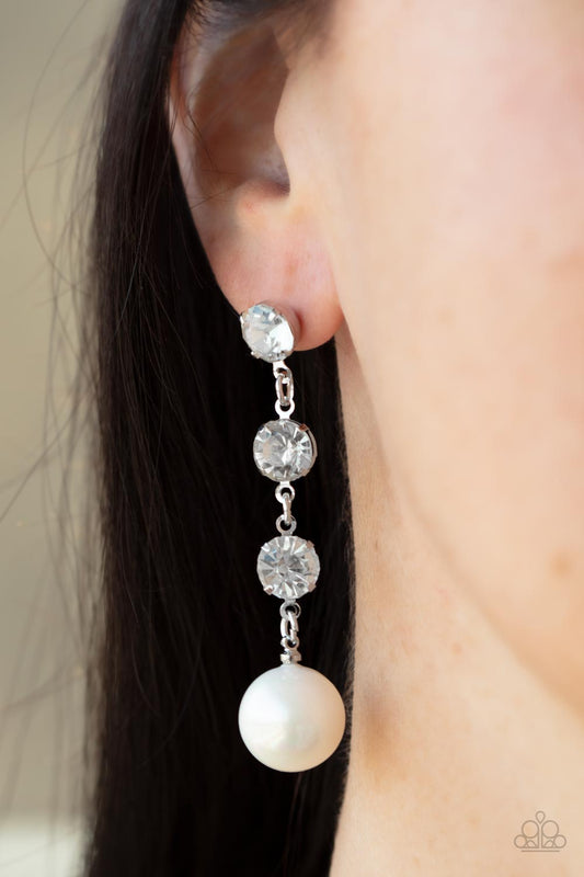 Yacht Scene White Pearl Earring - Paparazzi Accessories  Encased in sleek silver fittings, a trio of classic white rhinestones give way to an oversized iridescent pearl, creating an elegantly extended chandelier. Earring attaches to a standard post fitting.  All Paparazzi Accessories are lead free and nickel free!  Sold as one pair of post earrings.