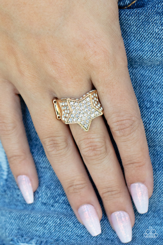 Here Come The Fireworks Gold Ring - Paparazzi Accessories  Encrusted in glittery white rhinestones, a sparkly gold star joins with a thick band of blinding white rhinestones. The edges of the star are embellished in additional white rhinestones, creating a stellar centerpiece atop the finger. Features a stretchy band for a flexible fit.  Sold as one individual ring.