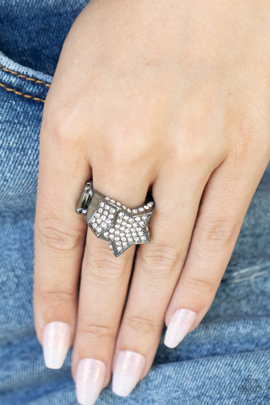 Here Come The Fireworks Black Ring - Paparazzi Accessories  Encrusted in glittery white rhinestones, a sparkly gunmetal star joins with a thick band of blinding white rhinestones. The edges of the star are embellished in additional white rhinestones, creating a stellar centerpiece atop the finger. Features a stretchy band for a flexible fit.  All Paparazzi Accessories are lead free and nickel free!  Sold as one individual ring.