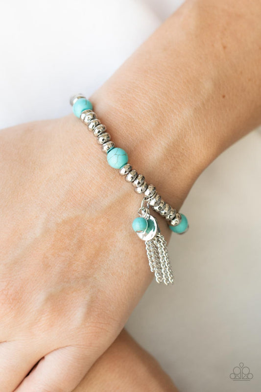 Whimsically Wanderlust Blue Bracelet - Paparazzi Accessories  An earthy collection of hammered silver beads and round turquoise stones are threaded along a stretchy band around the wrist. A dainty silver tassel, hammered silver disc, and a turquoise stone swing from the seasonal display, adding playful movement to the whimsy look.  All Paparazzi Accessories are lead free and nickel free!  Sold as one individual bracelet.