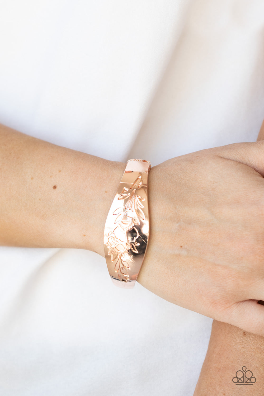 Fond of Florals Rose Gold Bracelet - Paparazzi Accessories  The front of a thick rose gold bangle-like bracelet is stamped in a leafy floral pattern, creating a whimsy centerpiece around the wrist. Features a hinged closure.  All Paparazzi Accessories are lead free and nickel free!  Sold as one individual bracelet.