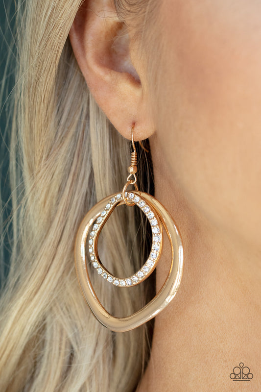 Spinning With Sass - Gold Item #P5IN-GDXX-051XX Featuring edgy asymmetrical shapes, a white rhinestone encrusted gold ring links to the top of a flattened gold ring, connecting into a smoldering lure. Earring attaches to a standard fishhook fitting.  Sold as one pair of earrings.