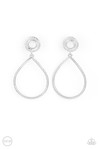 Fairytale Finish White Clip-On Earring - Paparazzi Accessories  A milky white bead is pressed into the center of a textured silver fitting that attaches to an oversized textured silver teardrop, creating an ethereal lure. Earring attaches to a standard clip-on earring.  Sold as one pair of clip-on earrings.