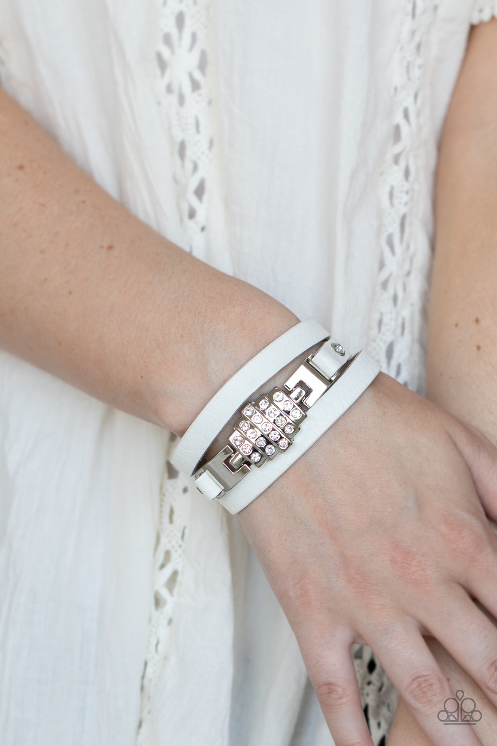 Ultra Urban White Bracelet - Paparazzi Accessories  A white rhinestone silver centerpiece is studded in place by white rhinestone encrusted silver studs across the spliced center of a white leather band, creating a glittery urban look around the wrist. Features an adjustable snap closure.  Sold as one individual bracelet.