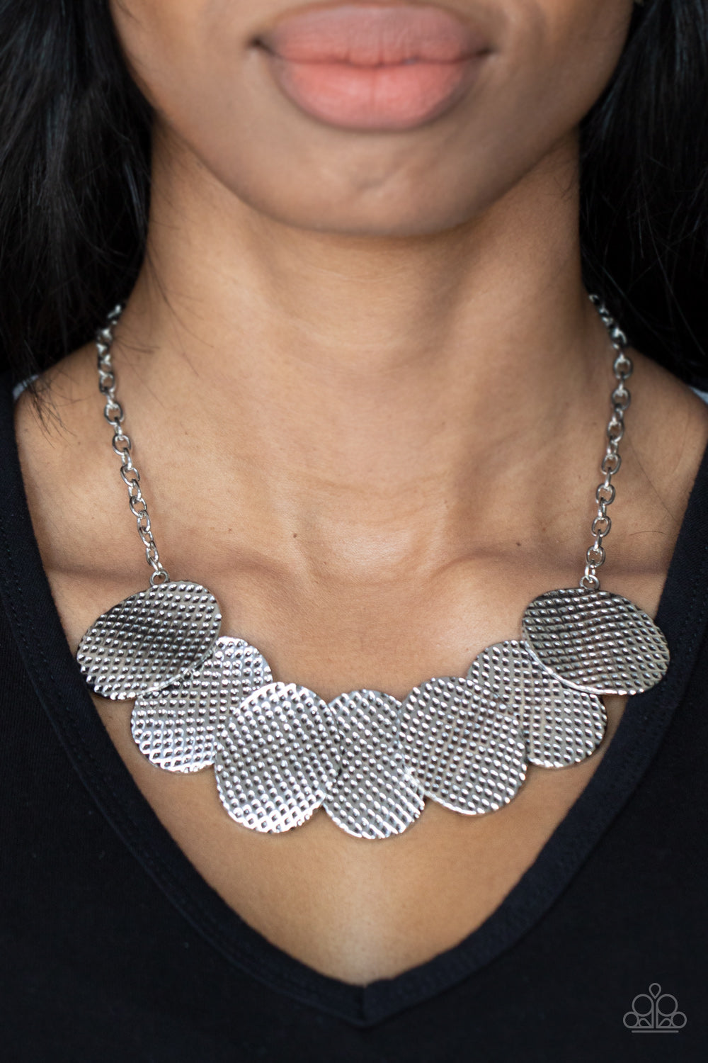 Industrial Wave Silver Necklace - Paparazzi Accessories Item #P2ST-SVXX-170XX A row of gently warped silver discs link together in an overlapping fashion as they connect on each end to a silver chain. Etched in a hammered antiqued silver finish, the oval discs create an edgy industrial effect below the collar. Features an adjustable clasp closure.  Sold as one individual necklace. Includes one pair of matching earrings.