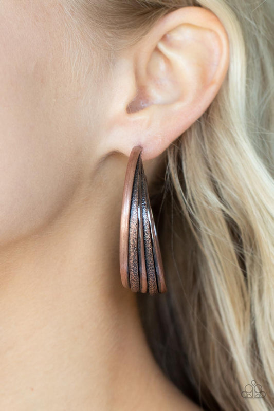 In Sync Copper Hoop Earring - Paparazzi Accessories  Antiqued textured copper rings alternate with shiny rings as they fuse together creating a curvy ribbon of rustic drama as they wrap around behind the ear. Earring attaches to a standard post fitting. Hoop measures approximately 2" in diameter.  Sold as one pair of hoop earrings.
